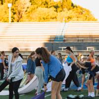 students setting out their yoga mats for yoga at sunset on the football field